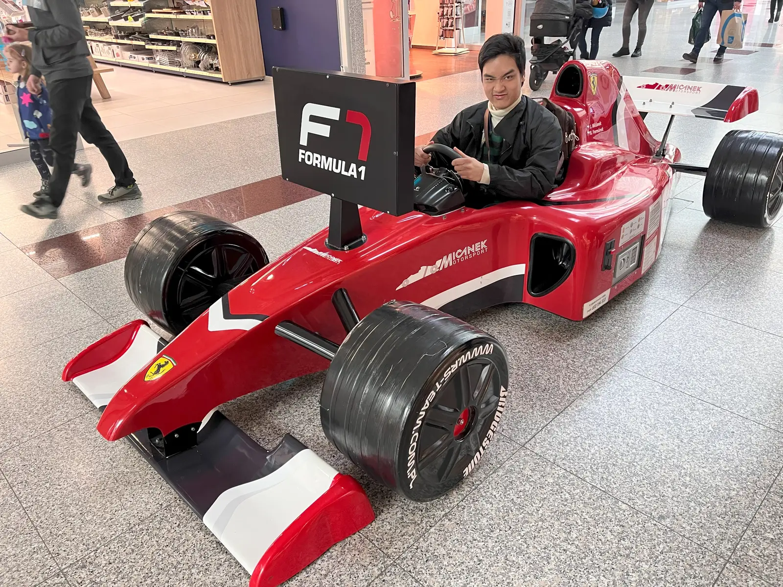 Vĩnh pulling a funny face in a red Formula 1 show car